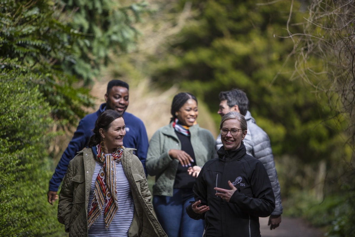 Group walking and talking and smiling together in a green space
